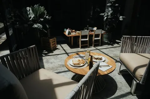 Sillones tejidos alrededor de una mesa redonda con platos y bebidas en el patio de Blackbird